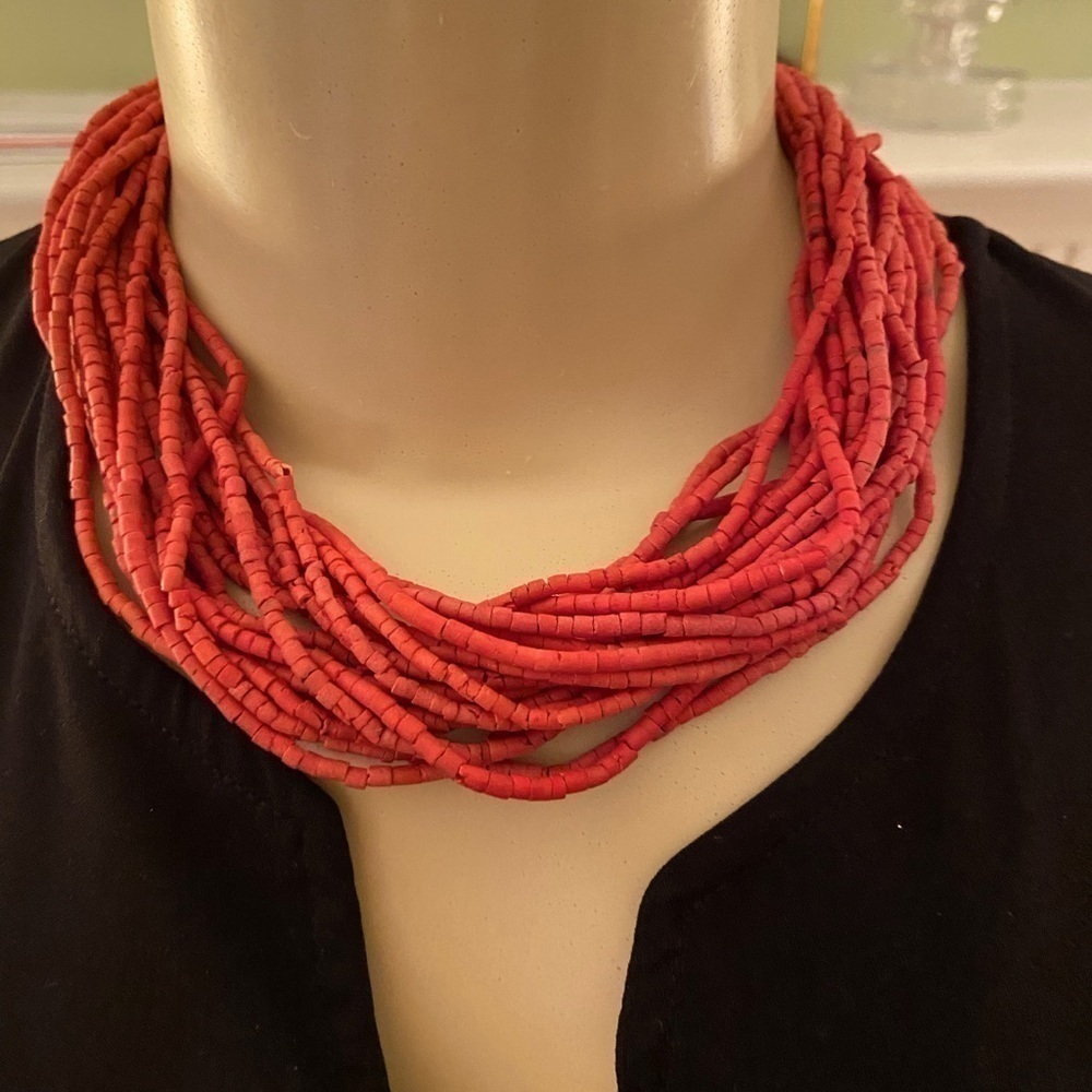 20 strands of beads undulate around your neck in bright terra cotta. Brightens.